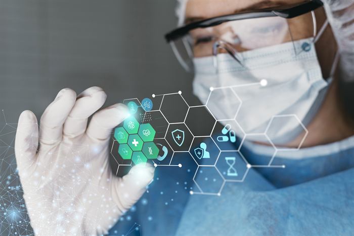 A technician in protective eyewear and gloves reviewing quality data
